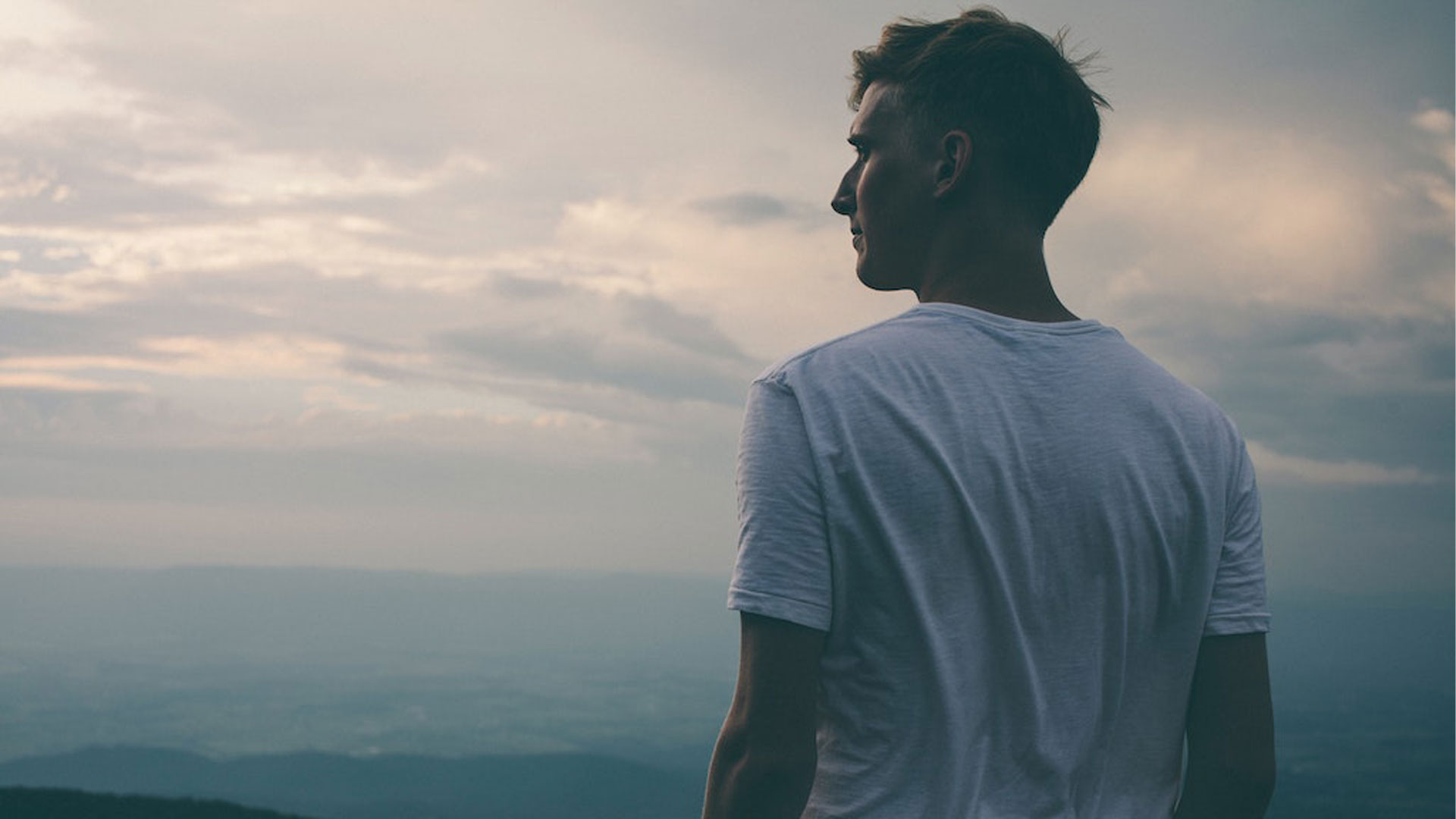 A man standing by the ocean staring at the horizon.